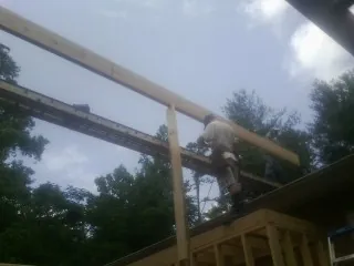 Carpenter setting a ridge beam over a new addition frame — Ice Dam Removal by Roofing Brothers in Pembroke